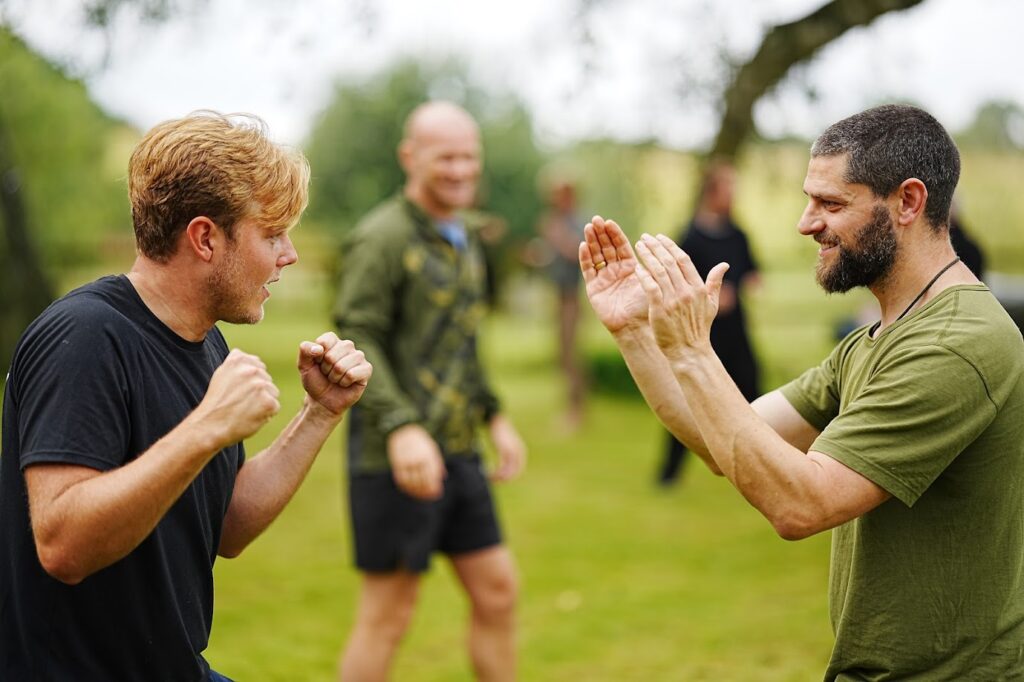 Men practising martial arts drills together outdoors at a Path of Manliness gathering